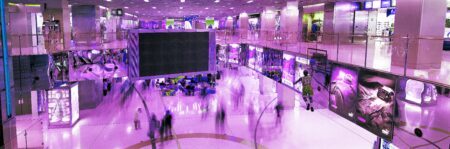 A purple-washed big mall space, with a big screen in the middle